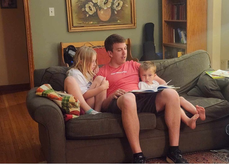 Klaus reading with two children on a couch